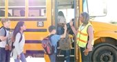 School bus driver giving high fives to students as they board the bus