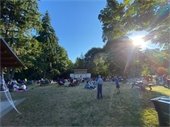 Crowd sitting in chairs and on blankets in a park setting