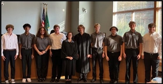 Judge Jennifer Grant and members of the Youth Court standing in front of the dais in the courtroom