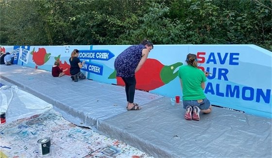 Volunteers helping paint the Save Our Salmon mural